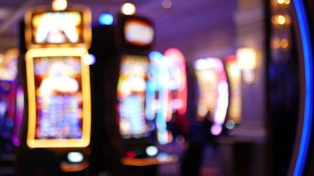 Defocused slot machines glow in casino on fabulous Las Vegas Strip, USA. Blurred gambling jackpot slots in hotel near Fremont street. Illuminated neon fruit machine for risk money playing and betting.