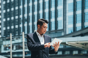 Business man using tablet in city outdoor with office building in the background stock photo
