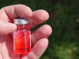 red bottle with medicine in hand on a Sunny day