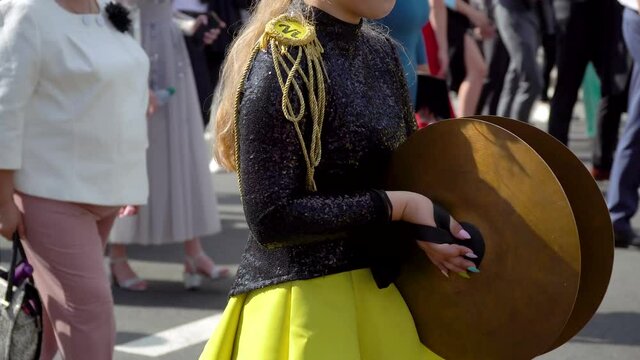 Street performance of festive march of drummers girls in yellow black costumes on city street. Street music concept