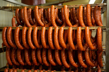 Sticks salami or sausages hanging on the ropes in the refrigerator. Production and sales of sausages.