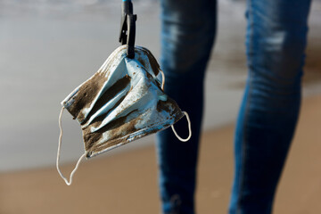 collecting a used surgical mask on the beach
