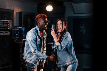 Two multi ethnic friends have a vocal practice in the studio together