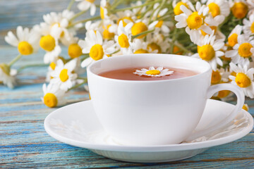 Chamomile flowers for tea brewing and a bouquet of Matricaria chamomilla on a wooden background.