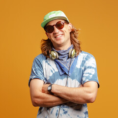 Studio portrait of a young man with long hairs in a green cap and headphones. Yellow background. Musician DJ