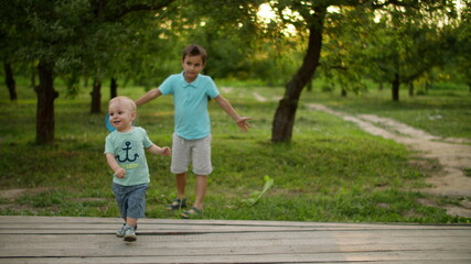 Cute brothers playing in summer park. Smiling siblings spending time together