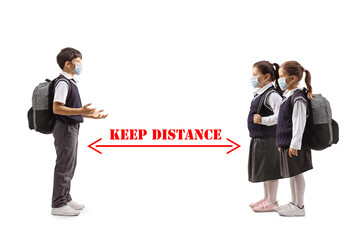 Schoolboy wearing a protective face mask and talking to schoolgirls with social distancing