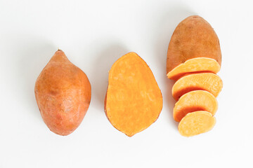 Farm raised organic sweet potato tubers laid in composition on textured background. The edible tuberous root vegetable on table counter. Clean eating concept. Background, close up, flat lay, top view.