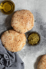Homemade pita bread with pesto and olive oil served on a gray marble table. Top view, vertical, copy space