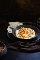 Hummus - chickpea dip - served in a ceramic bowl with smoked paprika and pita bread on a dark vintage background. Close-up, selective focus, copy space