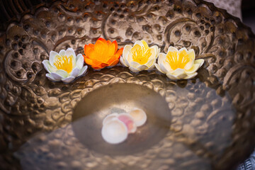 Obraz na płótnie Canvas White and orange lotus flowers float in a copper dish. At the bottom of the bowl are seashells. Spa, relaxation concept. A symbol of spiritual disclosure, wisdom, an image of purity and perfection.
