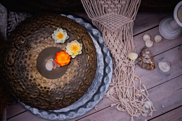 White and orange lotus flowers float in a copper dish. At the bottom of the bowl are seashells. Spa, relaxation concept. A symbol of spiritual disclosure, wisdom, an image of purity and perfection.