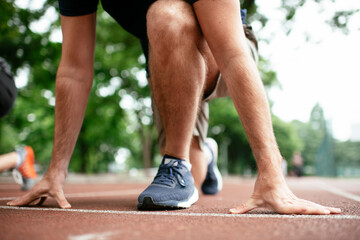 Athlete men in sportswear in start position for running. Close up..
