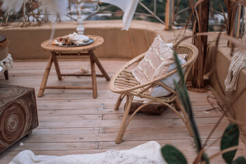 Decorate interior on an open terrace overlooking the city. In maracans, Indian, eco style in sand color: wicker furniture, macrame, lanterns with candles, glass lamps, pampas grass, poufs, a low table