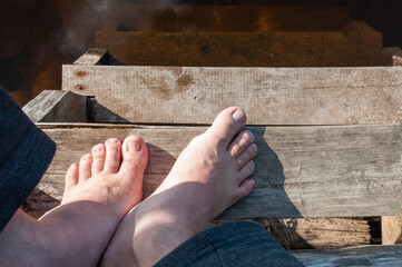 men's feet without shoes on steps above the water