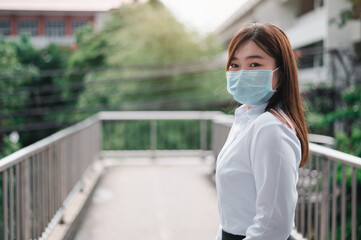 Fototapeta na wymiar Asian woman wearing a mask Standing at the overpass waiting for a rail car in the subway. Unemployed young women holding a job application. Covid 19 Concept, Development concept, Business concept.