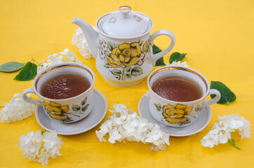 tea party for two. Teapot and two cups of tea on a yellow background. Porcelain tea set.