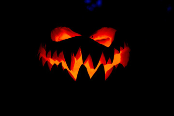 Fototapeta premium An evil winking hand-carved pumpkin frightening at Halloween