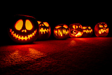 A scary gang of hand-carved pumpkins all lit up and ready for Halloween mischief