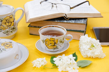 tea drinking. Teapot and a cup of tea on a yellow background. Porcelain tea set with bookshelf and glasses. Leisure concept.