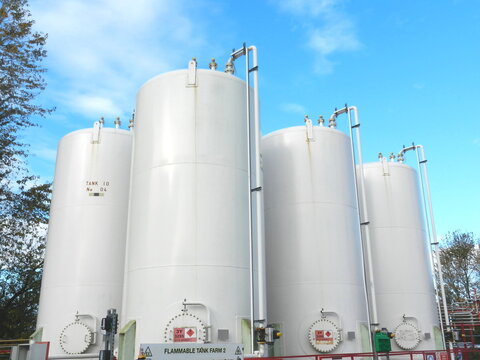 Large Bulk Industrial Liquid Containers Against Blue Sky Background 