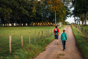 gens marchant sur un chemin de campagne.
père avec son fils marchant