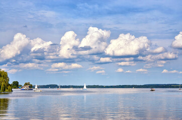 Sky with gigantic clouds over a lake with sailing boats and motor boats.