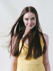 Fototapeta premium Beautiful brunette with long smooth hair in yellow shirt natural portrait over white background