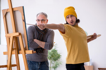 Old man taking lesson from young painter