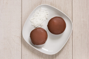 Top view of two round chocolate pies with coconut filling on white plate on the white background