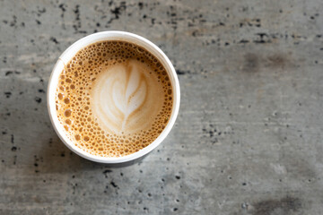 Coffee cup with latte art foam on wood table in coffee shop with copy space.Coffee is one of the...