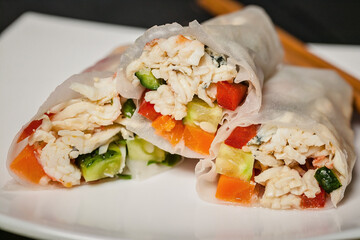 Close-up rice spring rolls with crab meat and vegetables on a white plate and bamboo sticks. Vietnamese seafood cuisine