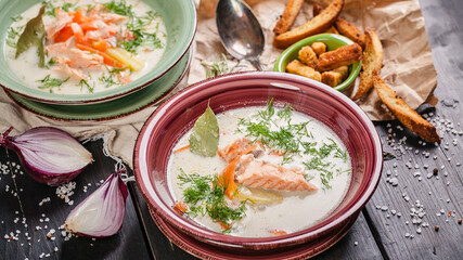 Finnish fish soup with salmon, cream, vegetables, fresh herbs and croutons. Traditional national cuisine. Seafood banner format