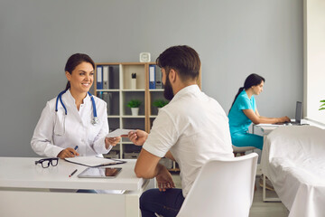 The doctor gives the patient a prescription while sitting at the table in the office of the clinic.Medical consultation.