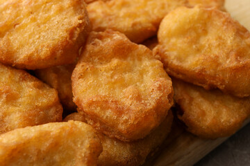 Tasty fried chicken nuggets on wooden board, close up