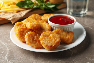 Composition with chicken nuggets, potato and sauces on gray table