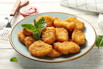 Composition with plate of chicken nuggets on white wooden background