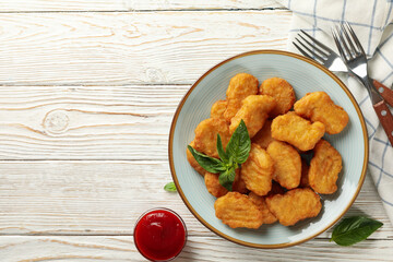 Composition with plate of chicken nuggets on white wooden background