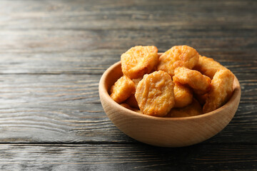 Bowl with fried chicken nuggets on wooden background
