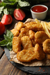 Composition with chicken nuggets, sauces and potato on wooden background