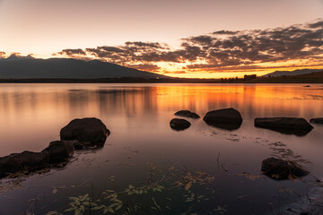 Beautiful long exposhure sunset landscape . The small lake with stones in the water, beautiful panorramic viwe on the mountais after sunset.
