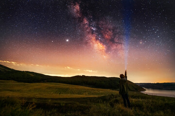 Beautiful starry sky with bright milky way galaxy. Night landscape . Person silhouette with flashlight illuminate starry sky. - obrazy, fototapety, plakaty