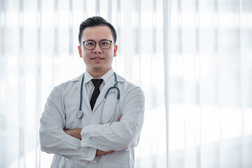 portrait asian doctor wearing eyeglass in suit uniform arm cross posing and looking at camera.white background in hospital.