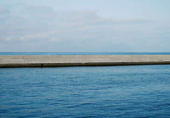 Fototapeta na wymiar Le linee del mare all’orizzonte e della diga foranea a protezione del porto. 