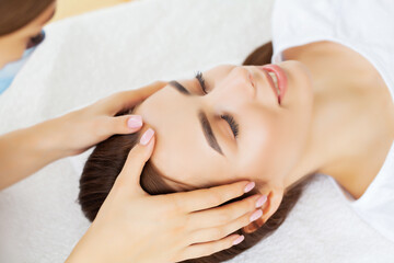 Fototapeta na wymiar Young pretty woman enjoying face massage procedure