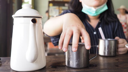 Woman who wear facial mask is handing ice cup in food shop