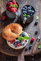 Tasty bagel with raspberries and blueberries for quick lunch