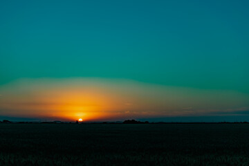 Beautiful evening sunset over a field of Golden ears of wheat and barley. Yellow is the rich color of the Sunny sky and wide spacious meadows with crops