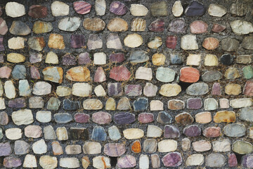 Wall lined with colored stones. Original texture.