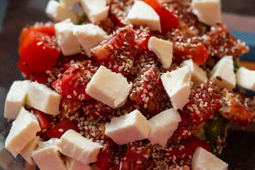 close-up of a fresh healthy salad with tomatoes, cheese, sesame seeds and flax seeds